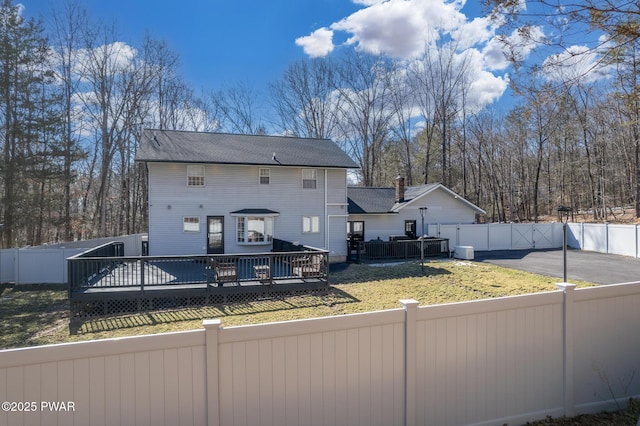 rear view of property with a yard, a gate, a fenced backyard, and a wooden deck