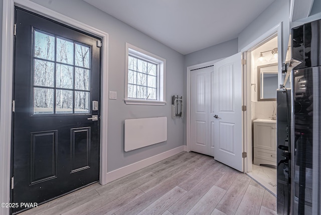 doorway with light wood finished floors and baseboards