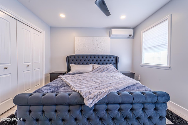 bedroom with a wall unit AC, a closet, wood finished floors, and recessed lighting