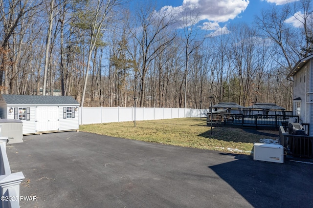 view of yard featuring a storage shed, an outdoor structure, fence, and a wooden deck