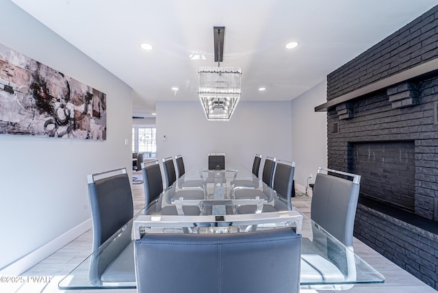 dining area featuring baseboards, recessed lighting, a fireplace, and an inviting chandelier