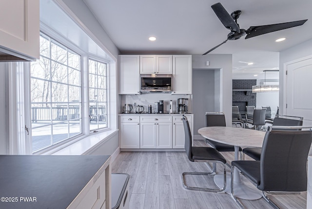 kitchen featuring light wood finished floors, ceiling fan, white cabinets, and decorative backsplash