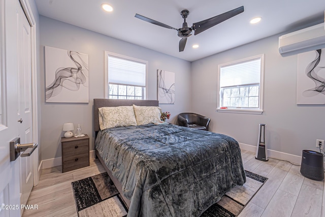 bedroom featuring light wood-type flooring, a wall unit AC, recessed lighting, and multiple windows