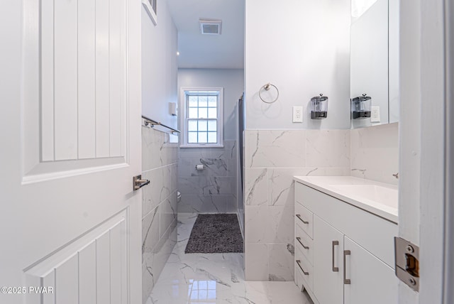 full bathroom featuring marble finish floor, visible vents, vanity, and tiled shower