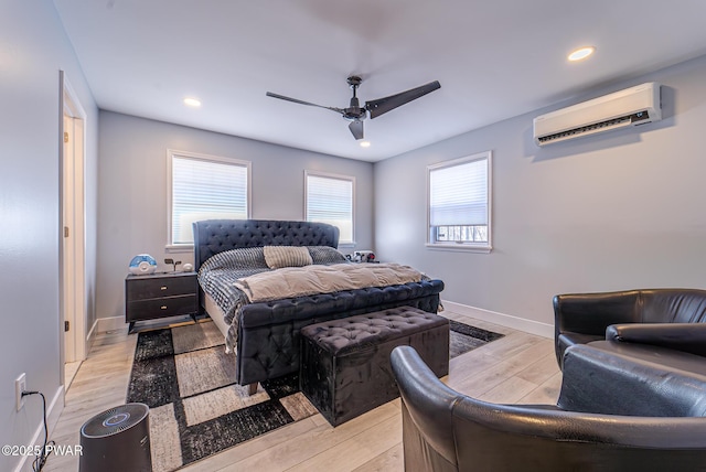 bedroom with light wood-style floors, a wall mounted air conditioner, and baseboards