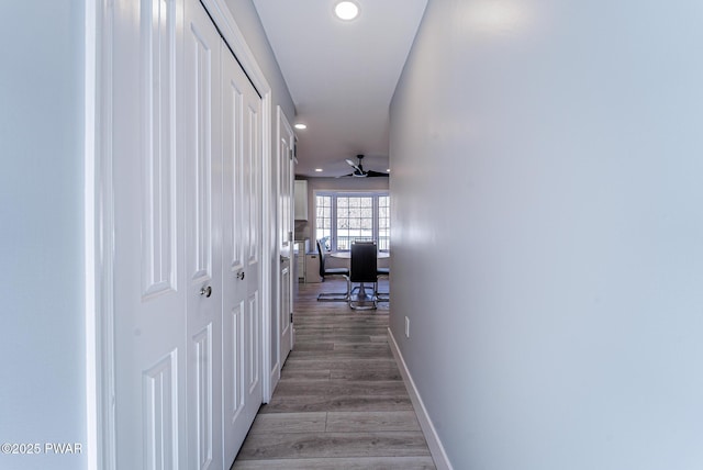 corridor featuring baseboards, wood finished floors, and recessed lighting