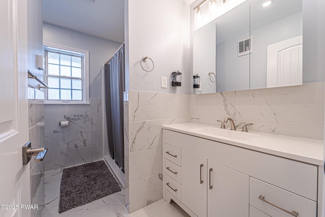 bathroom with marble finish floor, tile walls, visible vents, vanity, and a shower with curtain