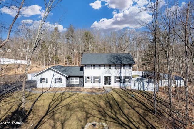 back of property featuring stone siding, a lawn, and fence