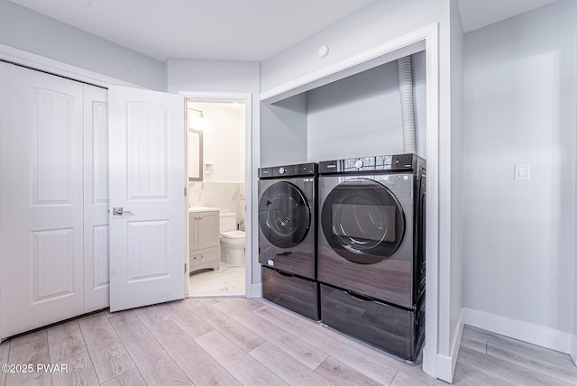 laundry area with light wood-type flooring, laundry area, independent washer and dryer, and tile walls