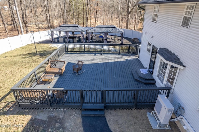 wooden terrace with a gazebo, ac unit, and a fenced backyard