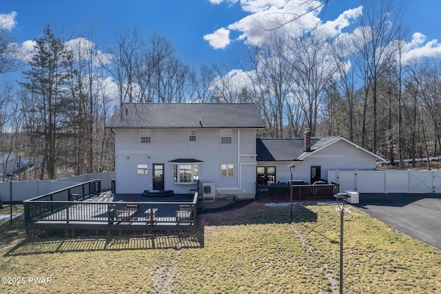 rear view of property with a wooden deck, fence, and a yard