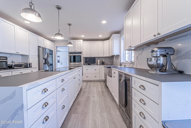 kitchen featuring tasteful backsplash, wine cooler, stainless steel appliances, light wood-type flooring, and a sink