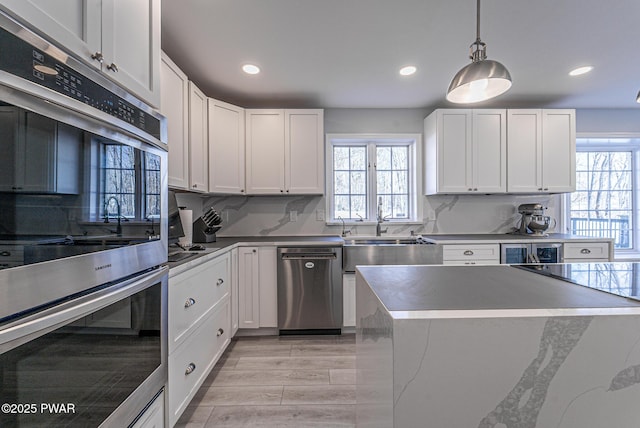 kitchen featuring appliances with stainless steel finishes, a sink, a wealth of natural light, and white cabinets