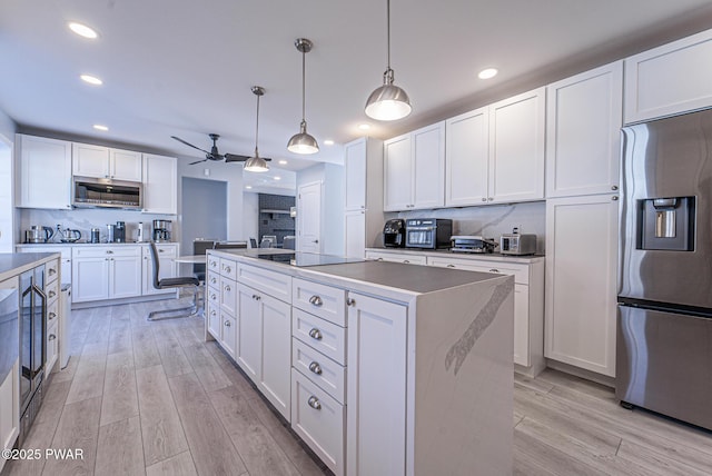 kitchen with light wood-type flooring, tasteful backsplash, stainless steel appliances, and a center island