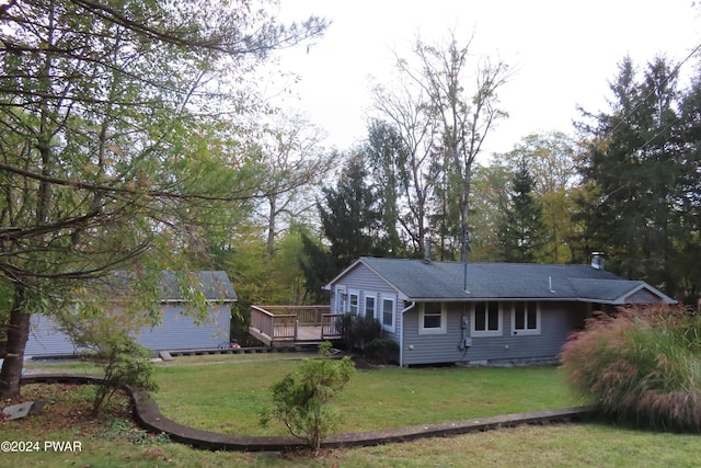 rear view of house featuring a wooden deck and a yard