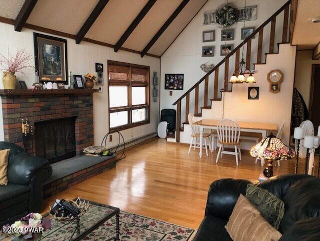 living room featuring high vaulted ceiling, a brick fireplace, a baseboard radiator, beam ceiling, and wood-type flooring