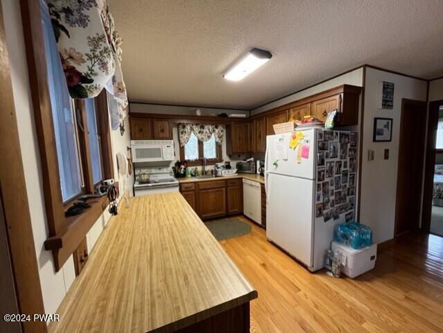 kitchen featuring a textured ceiling, light hardwood / wood-style flooring, white appliances, and sink