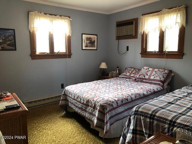 carpeted bedroom with an AC wall unit and a baseboard heating unit