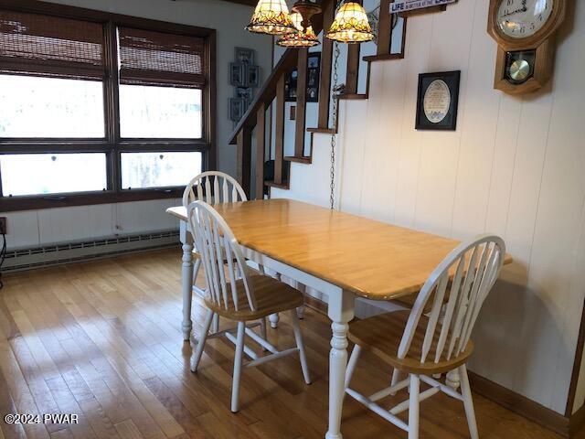 dining area with a baseboard radiator, hardwood / wood-style flooring, and a notable chandelier