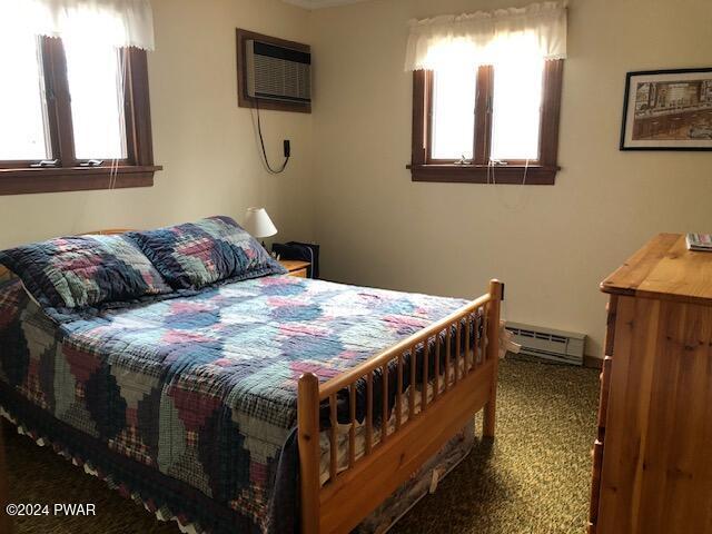 bedroom featuring carpet, a baseboard radiator, an AC wall unit, and multiple windows