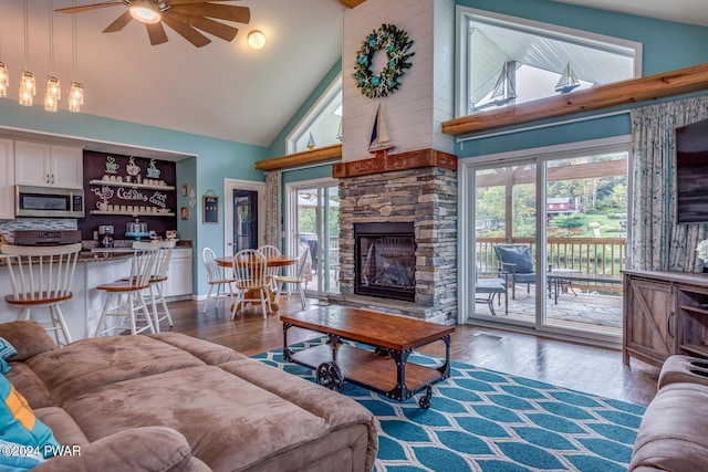 living room with a fireplace, hardwood / wood-style flooring, high vaulted ceiling, and ceiling fan