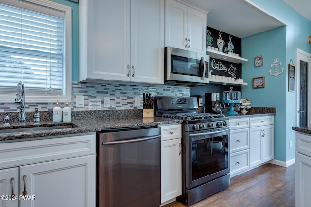 kitchen with white cabinetry, sink, dark stone countertops, decorative backsplash, and appliances with stainless steel finishes