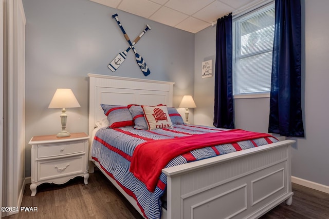 bedroom with dark hardwood / wood-style floors and a drop ceiling