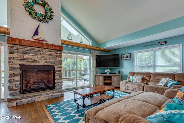 living room featuring plenty of natural light, a stone fireplace, wood-type flooring, and high vaulted ceiling