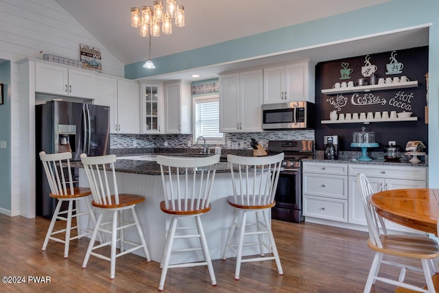 kitchen with white cabinets, a kitchen breakfast bar, a kitchen island, and appliances with stainless steel finishes