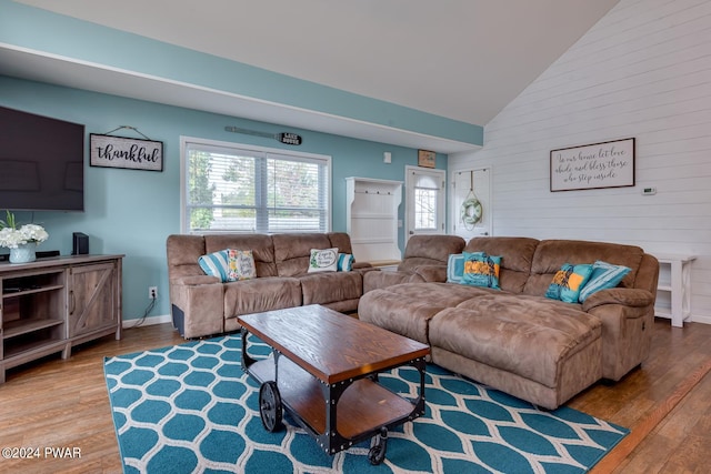 living room with hardwood / wood-style floors, wooden walls, and high vaulted ceiling