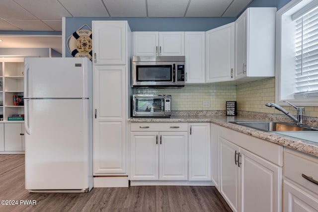 kitchen with white cabinets, a drop ceiling, white fridge, and sink