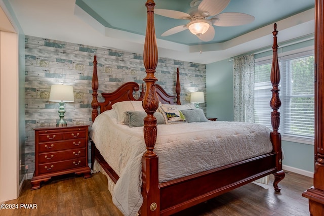 bedroom with a tray ceiling, multiple windows, ceiling fan, and dark hardwood / wood-style floors