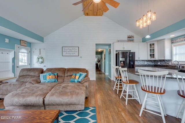 living room with light wood-type flooring, high vaulted ceiling, ceiling fan, and sink