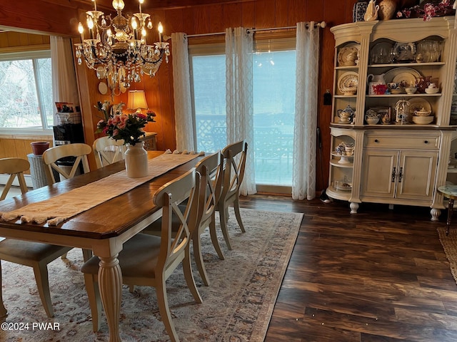 dining area with wood walls, dark hardwood / wood-style flooring, and an inviting chandelier