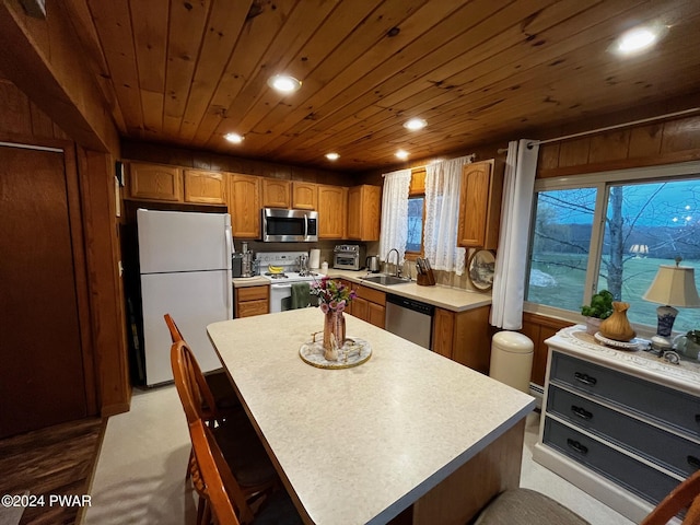 kitchen with sink, wooden ceiling, wooden walls, a kitchen island, and appliances with stainless steel finishes