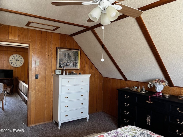 bedroom with dark carpet, a textured ceiling, ceiling fan, wooden walls, and lofted ceiling