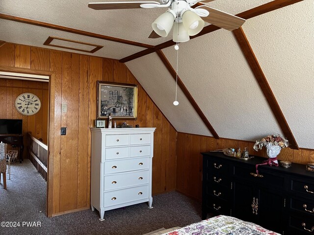 bedroom with dark carpet, a textured ceiling, ceiling fan, wooden walls, and lofted ceiling