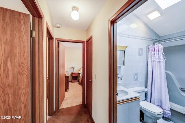 hallway featuring light colored carpet, sink, and tile walls