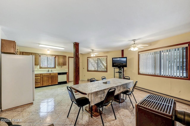 dining area featuring ornate columns, baseboard heating, ceiling fan, and sink