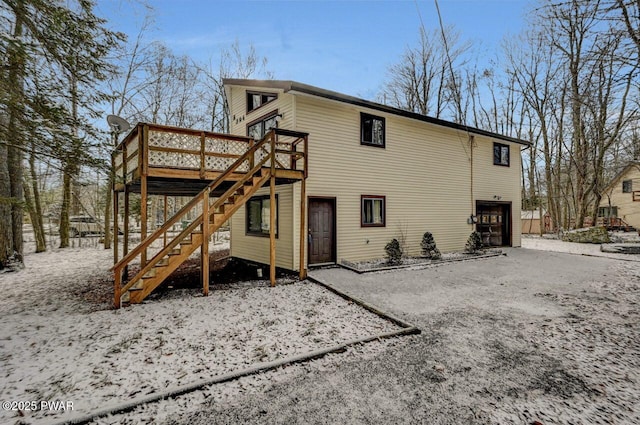 snow covered property featuring a garage and a deck