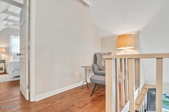 sitting room featuring lofted ceiling, baseboards, and wood finished floors
