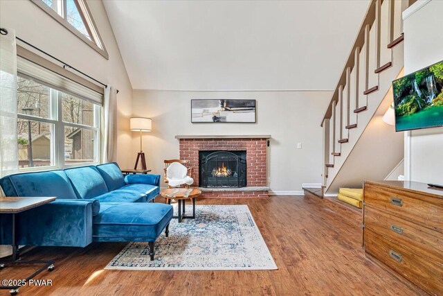living room featuring wood finished floors, a brick fireplace, high vaulted ceiling, and plenty of natural light