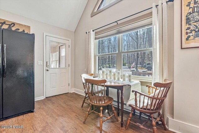 dining area featuring baseboards, vaulted ceiling, and wood finished floors