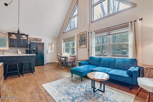 living area with high vaulted ceiling and light wood-style flooring