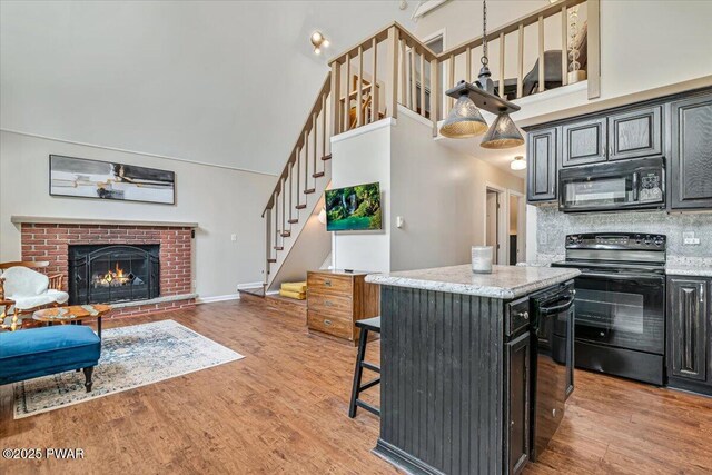 kitchen featuring a high ceiling, light wood finished floors, and black appliances