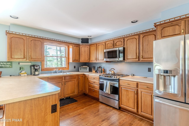 117 Circle Dr, Hawley, PA 18428 - kitchen featuring light countertops, brown cabinets, a sink, light wood-style flooring, and stainless steel appliances
