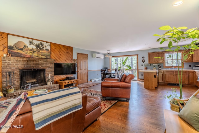 117 Circle Dr, Hawley, PA 18428 - living area featuring wooden walls, a fireplace, an AC wall unit, wood finished floors, and a baseboard heating unit