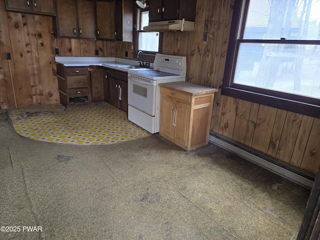 kitchen with electric stove, a sink, wood walls, and light countertops