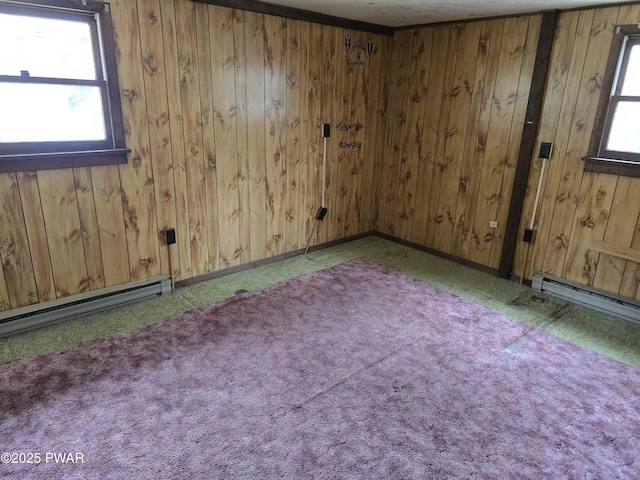 carpeted spare room with wooden walls and baseboard heating