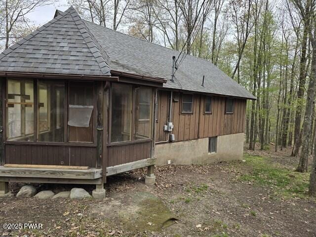 view of side of home featuring a sunroom and roof with shingles